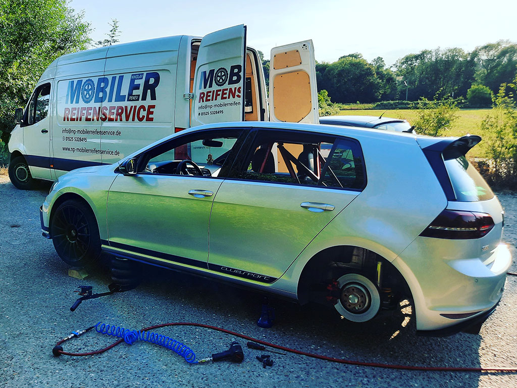 Aufgebockter VW Golf mit demontiertem Hinterrad und Werkzeug neben dem mobilen Reifenservice